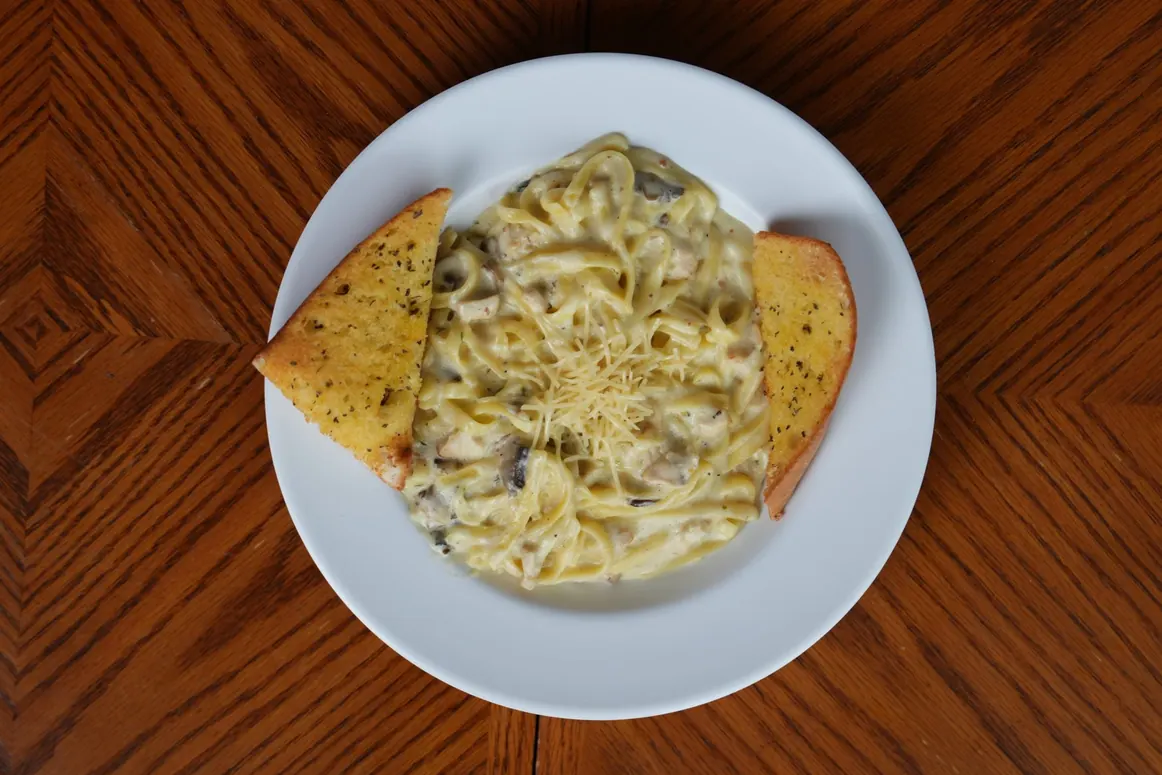 Fettuccine in Alfredo sauce with chicken and mushrooms, served with two slices of garlic bread, at Castello Pizza & Pasta on Rainier Ave S