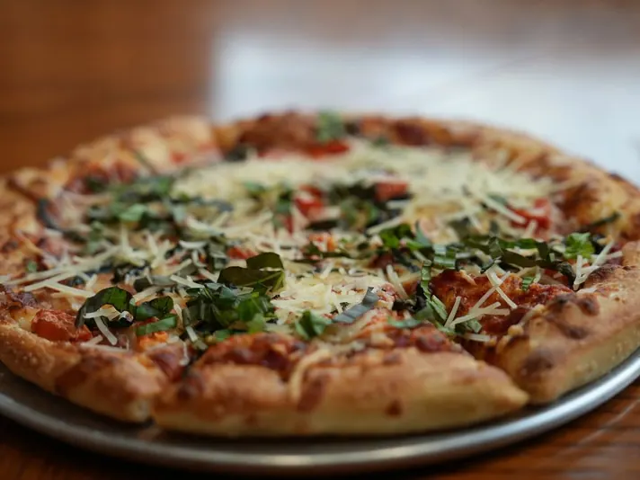 Pizza topped with fresh basil and shaved parmesan